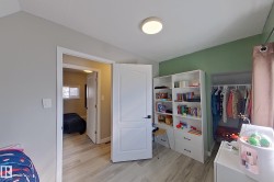 This room features light-toned flooring, a light green accent wall, and a built-in shelving unit with drawers - 