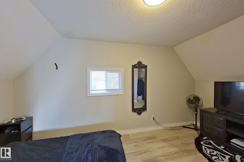 This room features a window with blinds, sloped ceilings, and wood-look flooring - 9328 106A Avenue, Edmonton, AB - Indoor Photo Showing Bedroom