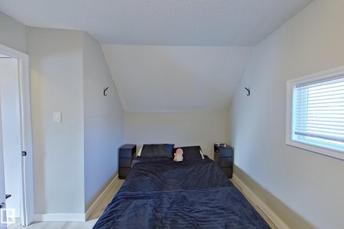 The property features light-colored walls, a window with blinds, and light-colored flooring - 9328 106A Avenue, Edmonton, AB - Indoor Photo Showing Bedroom