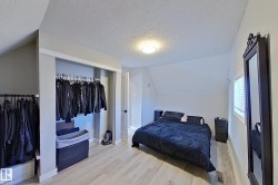 Bedroom with light-colored flooring, a window with blinds, and a built-in closet with hanging rails - 