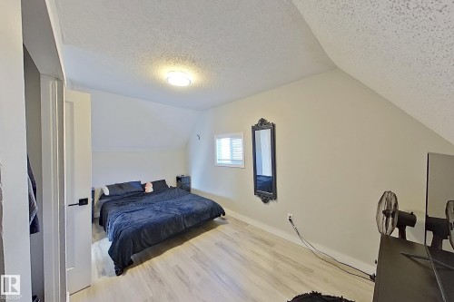 The room features light-colored flooring, a window providing natural light, and a sloped ceiling - 9328 106A Avenue, Edmonton, AB - Indoor Photo Showing Bedroom