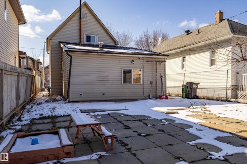 The property features a rear exterior with beige siding, a concrete patio, and a wooden sandbox - 9328 106A Avenue, Edmonton, AB - Outdoor With Exterior