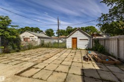 Spacious paved patio area with a detached storage shed featuring horizontal siding and a wood door - 