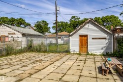 Paved patio area with concrete pavers, featuring a storage shed with vinyl siding and a wooden door - 