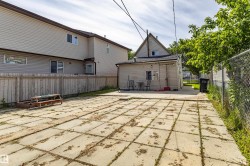 Expansive concrete patio area with a privacy fence and chain-link fencing, complemented by an accessory building with a window - 