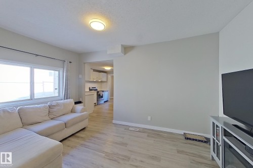 Living area featuring light-toned flooring, a window providing natural light, and a ceiling light fixture - 9328 106A Avenue, Edmonton, AB - Indoor Photo Showing Living Room