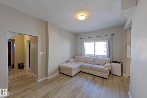 Living area featuring light-colored flooring, neutral-toned walls, and a window with curtains - 9328 106A Avenue, Edmonton, AB - Indoor