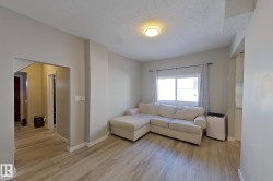 Living area featuring light-colored flooring, neutral-toned walls, and a window with curtains - 