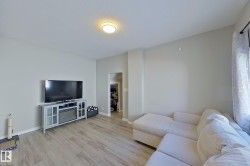 Living room with light-toned walls and wood-look flooring - 