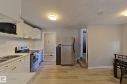 The kitchen features stainless steel appliances, white cabinetry, a double basin sink, and light-toned flooring - 
