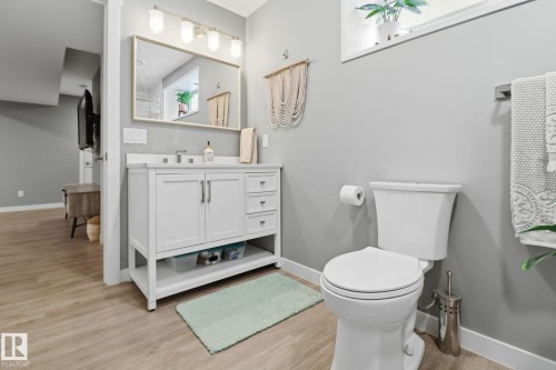 Bathroom featuring a white vanity with a countertop sink, a mirror with an overhead light fixture, a toilet, and light-toned flooring - 430 Watt Boulevard, Edmonton, AB - Indoor Photo Showing Bathroom