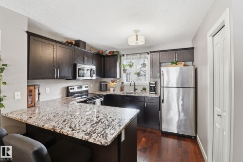 The kitchen features dark wood cabinetry, light-colored granite countertops, and stainless steel appliances - 430 Watt Boulevard, Edmonton, AB - Indoor Photo Showing Kitchen With Upgraded Kitchen