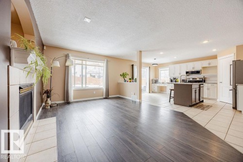 The property features an open-concept living area with dark wood-style flooring and a tiled fireplace - 7 Doucette Place, St. Albert, AB - Indoor Photo Showing Kitchen