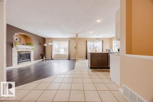 The property features a spacious open-plan living area with varied flooring, including light-colored tile and dark wood-style flooring - 7 Doucette Place, St. Albert, AB - Indoor With Fireplace