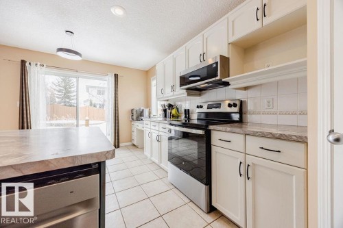 The kitchen features white cabinetry, a built-in microwave, an oven with a cooktop, and a dishwasher - 7 Doucette Place, St. Albert, AB - Indoor Photo Showing Kitchen