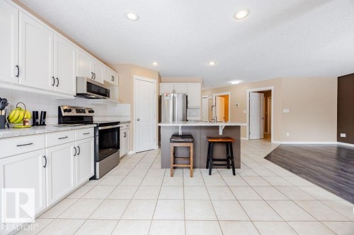 The kitchen features white cabinetry, stainless steel appliances, and an island with seating - 7 Doucette Place, St. Albert, AB - Indoor Photo Showing Kitchen