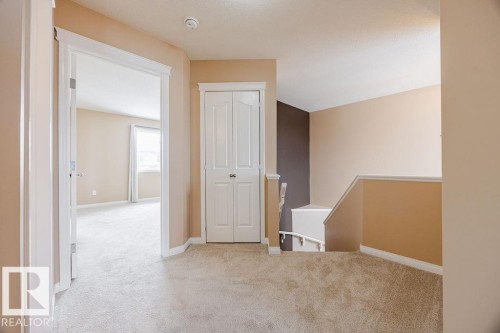 The property features light-colored carpeting, neutral painted walls, white trim, and a white interior door - 7 Doucette Place, St. Albert, AB - Indoor Photo Showing Other Room