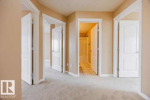 The property features neutral-toned walls, light-colored carpeting, and white trim throughout the hallway - 7 Doucette Place, St. Albert, AB - Indoor Photo Showing Other Room