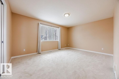 This room features neutral-toned carpet flooring, light-colored walls, and a window with a view of trees - 7 Doucette Place, St. Albert, AB - Indoor Photo Showing Other Room
