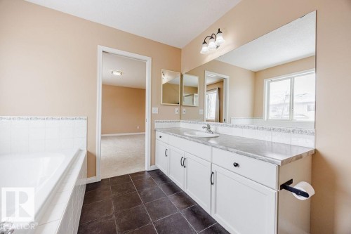 Bathroom featuring a spacious vanity with white cabinetry, a large mirror, and a built-in bathtub - 7 Doucette Place, St. Albert, AB - Indoor Photo Showing Bathroom