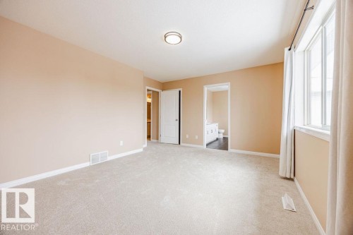 Expansive room featuring light-colored carpet, neutral wall tones, and a large window with drapes - 7 Doucette Place, St. Albert, AB - Indoor Photo Showing Other Room