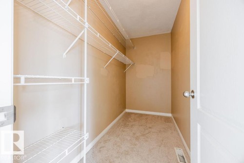 This property features a closet with wire shelving and a hanging rod, carpeted flooring, and a white door with a chrome doorknob - 7 Doucette Place, St. Albert, AB - Indoor With Storage