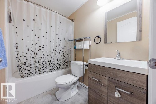 Bathroom featuring a white bathtub, a toilet, a vanity with a white sink, and a mirror - 7 Doucette Place, St. Albert, AB - Indoor Photo Showing Bathroom