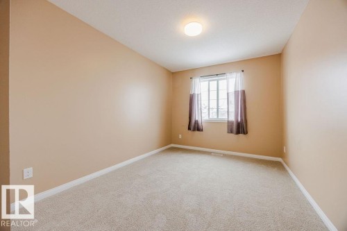 The property features a room with light beige walls, light-colored carpeting, a window with curtains, and a ceiling light fixture - 7 Doucette Place, St. Albert, AB - Indoor Photo Showing Other Room