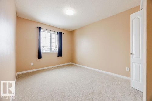 Bright room featuring light-toned walls, neutral carpeting, a window with dark curtains, and a white paneled door - 7 Doucette Place, St. Albert, AB - Indoor Photo Showing Other Room