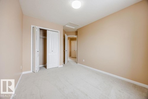 This room features neutral-toned walls, light-colored carpeting, and a closet with bi-fold doors - 7 Doucette Place, St. Albert, AB - Indoor Photo Showing Other Room