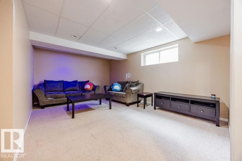 The property features a spacious room with light-colored carpeting, a drop ceiling with recessed lighting, and a window providing natural light - 7 Doucette Place, St. Albert, AB - Indoor Photo Showing Other Room