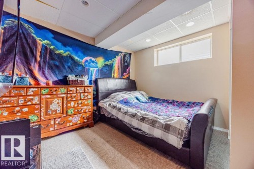 The room features a window providing natural light, a drop ceiling with recessed lighting, and carpeted flooring - 7 Doucette Place, St. Albert, AB - Indoor Photo Showing Bedroom