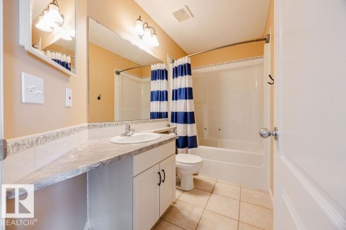 This bathroom features a vanity with a countertop and an integrated sink, a mirror, and a full-size bathtub with a shower - 7 Doucette Place, St. Albert, AB - Indoor Photo Showing Bathroom