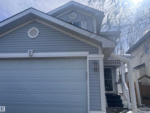 The property features light blue siding, a white garage door, and a white pergola entry - 7 Doucette Place, St. Albert, AB - Outdoor