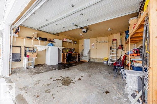 The property features an attached garage with a concrete floor, an overhead garage door, interior shelving, and an interior door - 7 Doucette Place, St. Albert, AB - Indoor Photo Showing Garage