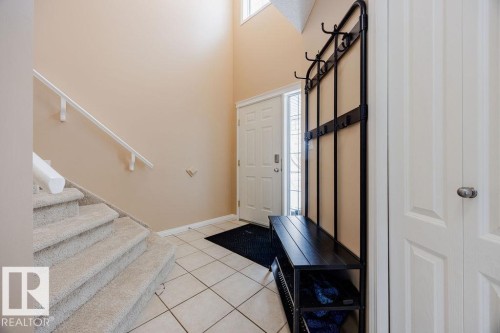 Entryway featuring a front door with a sidelight, tiled flooring, and a carpeted staircase with a white handrail - 7 Doucette Place, St. Albert, AB - Indoor Photo Showing Other Room