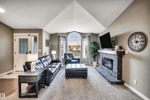 Living room featuring a vaulted ceiling, neutral toned walls, and carpeted floors - 5201 40 Avenue, Beaumont, AB - Indoor Photo Showing Living Room With Fireplace