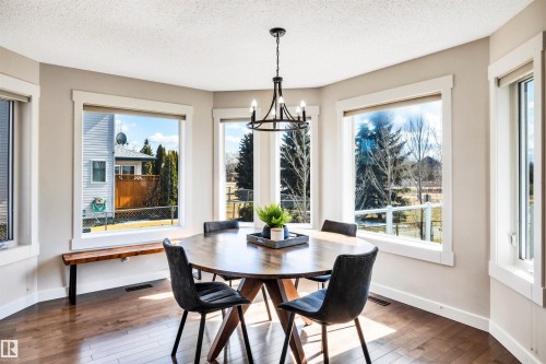 This dining area features hardwood floors and a modern chandelier - 5201 40 Avenue, Beaumont, AB - Indoor Photo Showing Dining Room