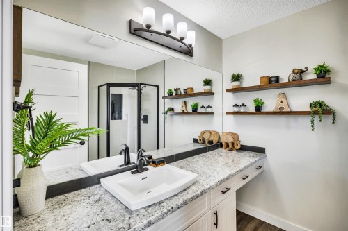 Bathroom featuring a large vanity with a white rectangular vessel sink, a granite countertop, and dark-toned fixtures - 5201 40 Avenue, Beaumont, AB - Indoor Photo Showing Bathroom