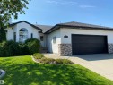 The property features a well-maintained lawn, established landscaping, and a driveway leading to an attached garage - 5201 40 Avenue, Beaumont, AB  - Outdoor 