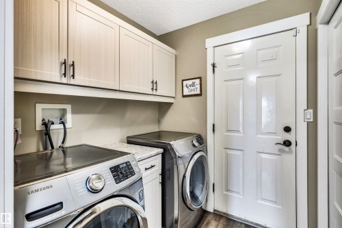 This property features a dedicated laundry area with overhead cabinetry, a countertop, and a white paneled door - 5201 40 Avenue, Beaumont, AB - Indoor Photo Showing Laundry Room