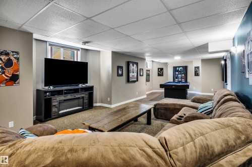 Spacious entertainment area featuring carpeted flooring, a large window, and recessed lighting - 5201 40 Avenue, Beaumont, AB - Indoor