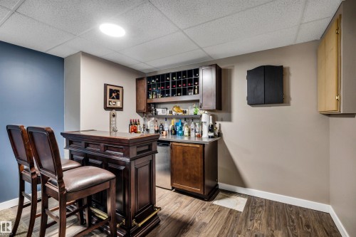 This dedicated space features a built-in bar with dark wood cabinetry, a wine rack, and a stainless steel countertop - 5201 40 Avenue, Beaumont, AB - Indoor Photo Showing Other Room