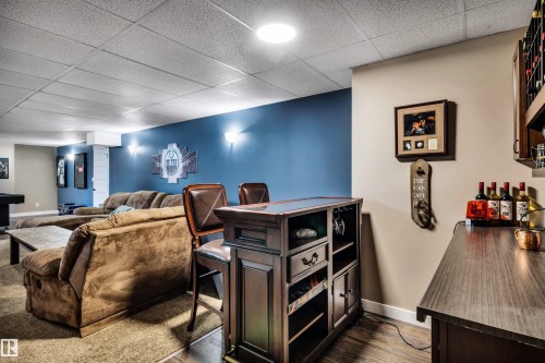 This inviting entertainment area features a built-in bar with a wine rack, a counter, and ample space for seating - 5201 40 Avenue, Beaumont, AB - Indoor