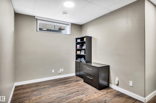 This room features wood-look flooring, light-colored walls, and a window providing natural light - 5201 40 Avenue, Beaumont, AB - Indoor Photo Showing Other Room