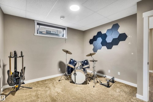 This versatile room features neutral-toned walls, carpeted flooring, and a drop ceiling with recessed lighting - 5201 40 Avenue, Beaumont, AB - Indoor Photo Showing Gym Room