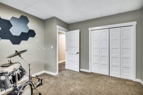 This room features a neutral color palette, carpeted floors, and white bi-fold closet doors - 5201 40 Avenue, Beaumont, AB - Indoor