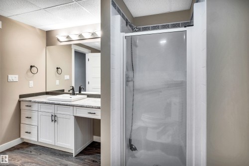 This bathroom features a contemporary vanity with a white vessel sink, dark fixtures, and a spacious mirror - 5201 40 Avenue, Beaumont, AB - Indoor Photo Showing Bathroom
