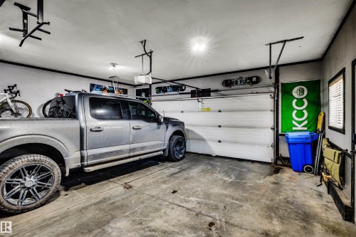 The property features a garage with a sectional overhead door, concrete flooring, and ceiling-mounted light fixtures - 5201 40 Avenue, Beaumont, AB - Indoor Photo Showing Garage