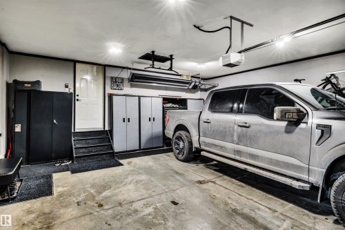 The garage features a concrete floor, bright overhead lighting, and storage cabinets - 5201 40 Avenue, Beaumont, AB - Indoor Photo Showing Garage